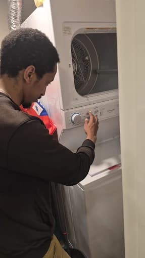 Technician servicing a stacked washer and dryer unit